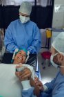 Visão frontal do homem que conforta a mulher grávida durante o trabalho de parto no teatro de operação no hospital — Fotografia de Stock