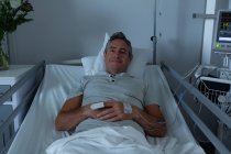 Портрет кавказского пациента-мужчины, расслабляющегося в палате, лежащего в постели в больнице — стоковое фото