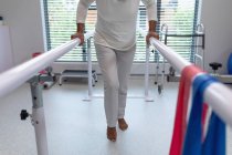 Low section of female patient walking with parallel bars in hospital — Stock Photo