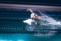 Seitenansicht eines männlichen kaukasischen Schwimmers in Schutzbrille und weißer Badekappe im Schwimmbad — Stockfoto
