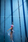 Vue en angle élevé d'une femme caucasienne portant un bonnet de bain rose et des lunettes faisant un coup de style libre dans une piscine — Photo de stock