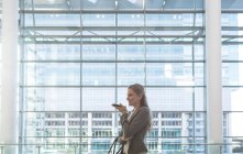 Vista lateral de la mujer de negocios hablando por teléfono móvil en el moderno edificio de oficinas - foto de stock