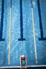 Hochwinkelaufnahme eines männlichen kaukasischen Schwimmers mit weißer Badekappe und Schutzbrille, der an der Seite des Schwimmbeckens hält — Stockfoto