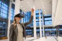 Frontansicht einer Geschäftsfrau mit Virtual-Reality-Headset in der Lobby eines modernen Büros — Stockfoto