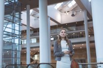 Vista frontale della donna d'affari che cammina vicino alla scala mobile in un moderno edificio per uffici — Foto stock