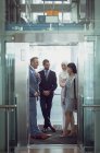 Vista frontal de diversos empresários usando elevador no escritório moderno — Fotografia de Stock
