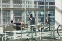Вид збоку різноманітних бізнесменів, що ходять в сучасному офісі — стокове фото