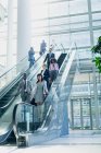 Seitenansicht diverser Geschäftsleute, die Rolltreppen in modernen Büros nutzen — Stockfoto