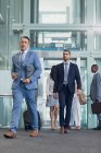 Vorderseite von kaukasischen männlichen Führungskräften, die im Flur moderner Büros wandeln — Stockfoto
