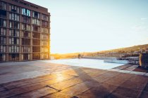 A swimming pool at the rooftop the view of a building and the sunset — Stock Photo