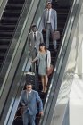 Front view of diverse business people using escalators in modern office — Stock Photo