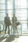 Frontansicht von Geschäftsleuten, die sich in der Nähe einer Rolltreppe in einem modernen Bürogebäude zusammenschließen — Stockfoto