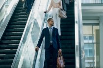 Front view of Caucasian businessman using escalators in modern office — Stock Photo