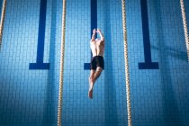 Vista ad alto angolo di un nuotatore caucasico maschio che indossa un cappello da nuoto bianco che si tuffa in piscina — Foto stock