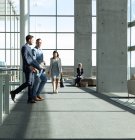 Vista lateral de executivos do sexo masculino caucasianos interagindo uns com os outros enquanto caminham no escritório moderno — Fotografia de Stock