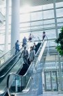 Vista lateral de diversos empresários usando escadas rolantes no escritório moderno — Fotografia de Stock