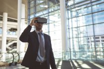 Vue de face d'un homme d'affaires utilisant un casque de réalité virtuelle dans un immeuble de bureaux moderne — Photo de stock