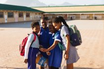 Vue de face gros plan d'un groupe de jeunes écolières africaines regardant un smartphone ensemble dans une aire de jeux de l'école élémentaire du canton — Photo de stock