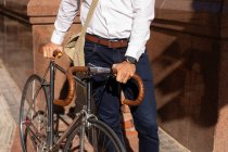 Front view mid section of man walking and wheeling his bicycle in the city. Digital Nomad on the go. — Stock Photo