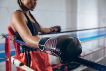 Close-up of female boxer resting in the corner of the boxing ring at boxing club. Strong female fighter in boxing gym training hard. — Stock Photo