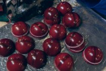 Elevado primer plano de las mitades exteriores en forma de bolas de cricket rojo en la línea de producción en un taller en una fábrica de equipos deportivos . - foto de stock