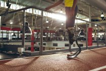 Sección baja de hombre discapacitado atlético de pie en pista de atletismo en el gimnasio - foto de stock