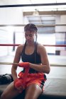 Front view of female boxer wearing hand wrap at boxing club. Strong female fighter in boxing gym training hard. — Stock Photo