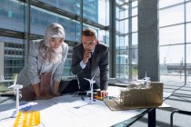 Multi-ethnic male and female architects looking at blueprint in office. — Stock Photo