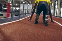 Rear view of disabled male athletic in starting position on running track in fitness center — Stock Photo