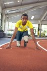 Вид спереди инвалида афроамериканского спортсмена в стартовой позиции на беговой дорожке в фитнес-центре — стоковое фото