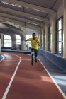 Вид спереди на инвалида афроамериканского спортсмена бегущего по спортивной трассе в фитнес-центре — стоковое фото