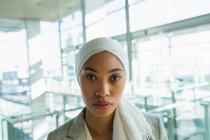 Nahaufnahme einer Geschäftsfrau im Hidschab, die in einem modernen Büro in die Kamera blickt. — Stockfoto