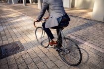 Rückansicht eines Mannes, der mit seinem Fahrrad in einer Straße in der Stadt unterwegs ist. Digitaler Nomade unterwegs. — Stockfoto