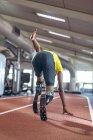 Vista trasera de la carrera atlética masculina discapacitada en pista deportiva en el gimnasio - foto de stock