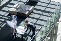 High angle view of male and female architects looking at blueprint in office. — Stock Photo