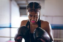 Крупный план женщины-боксера, практикующей бокс в боксерском клубе. Сильная женщина-боец в боксёрском зале тяжело тренируется . — стоковое фото