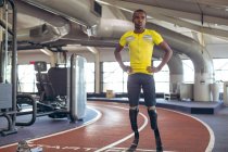 Frontansicht eines behinderten afrikanisch-amerikanischen männlichen Athleten, der auf der Laufbahn im Fitness-Center steht — Stockfoto
