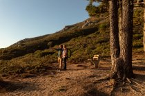 Vista laterale di un uomo e una donna caucasica matura che indossano zaini fermandosi a godersi il paesaggio e indicando la distanza durante un'escursione . — Foto stock