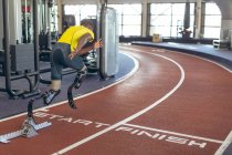 Visão traseira do atlético masculino afro-americano deficiente correndo em pista de corrida no centro de fitness — Fotografia de Stock