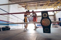 Two female boxers fighting in boxing ring at fitness center. Strong female fighter in boxing gym training hard. — Stock Photo
