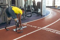 Side view of disabled African American male athletic at starting block on running track in fitness center — Stock Photo