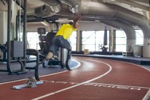 Rear view of disabled African American male athletic running on race track in fitness center — Stock Photo