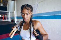 Primo piano della pugile che guarda la telecamera nel club di boxe. Forte combattente femminile in palestra di pugilato allenamento duro . — Foto stock