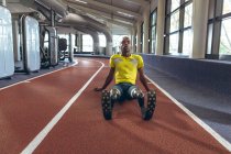 Vista frontal de deficientes afro-americanos masculino atlético relaxante em uma pista de corrida no centro de fitness — Fotografia de Stock