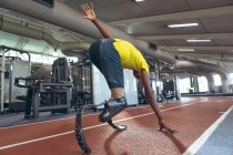 Rear view of disabled African American male athletic running on sports track in fitness center — Stock Photo