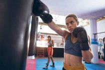 Boxe afro-americano praticando boxe no clube de boxe. Forte lutador feminino no treinamento de ginásio de boxe duro . — Fotografia de Stock