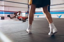 Unconscious female boxer lying in boxing ring at fitness center. Strong female fighter in boxing gym training hard. — Stock Photo