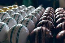 Primo piano di palline di cricket rosse, bianche e gialle in fila alla fine della linea di produzione in una fabbrica
. — Foto stock