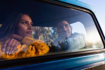 Jovem casal misto sentado em seu caminhão pick-up durante uma parada em uma viagem de carro . — Fotografia de Stock
