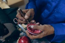 Primo piano delle mani dell'uomo che lavorano sulla cucitura delle metà esterne sagomate delle palline da cricket in un'officina in una fabbrica di attrezzature sportive . — Foto stock